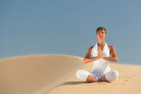 Yoga meditation on the beach, healthy female body in peace, woman sitting relaxed on sand over beautiful sea sunset, calm girl enjoying nature, active vacation lifestyle, zen spa, wellness conceptの写真素材