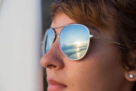 face surfer woman. Rear view of beautiful sexy young woman surfer girl in bikini with white surfboard on a beach at sunset or sunriseの写真素材