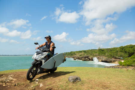 surfer man with surfboard and bike on the beachの写真素材