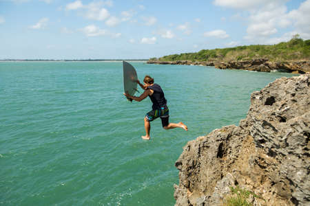 surfer jumps off a cliff into the ocean