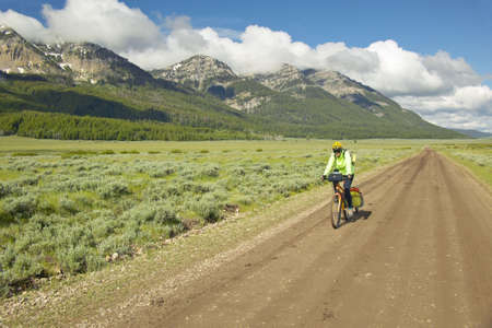 Bicyclist riding through spring flowers and mountains in Centennial Valley near Lakeview, MTのeditorial素材