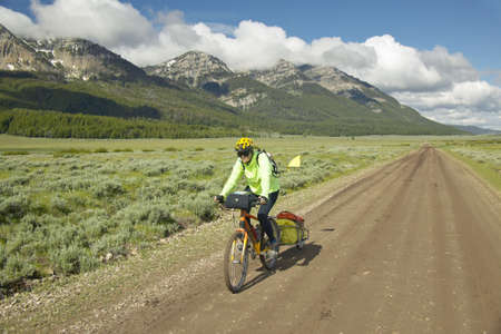 Bicyclist riding through spring flowers and mountains in Centennial Valley near Lakeview, MTのeditorial素材