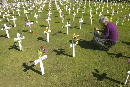 Woman kneels at mock cemetery honoring 1500+ Iraqi servicemen killed in Iraq War, Ventura Californiaのeditorial素材
