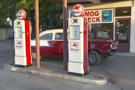 A vintage 1957 Chevy parked in front of antique gas pumps at Ernie's old auto garage in Santa Paula, CAのeditorial素材