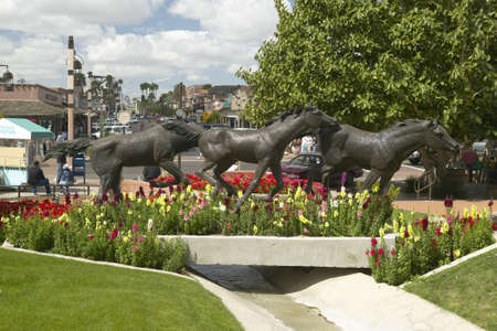 A sculpture of running horses and beautiful spring flowers in Old Town of Scottsdale, Arizonaのeditorial素材