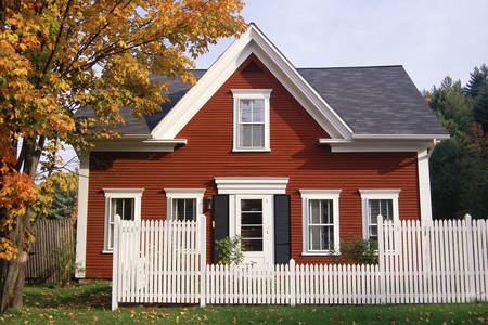 Red wooden house with white picket fence in autumn, New Englandのeditorial素材