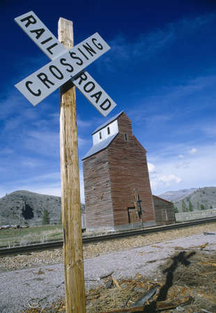 Railroad crossing sign with grain silo in background, Montanaのeditorial素材