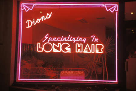 A neon sign that reads Dions, specializing in long hair