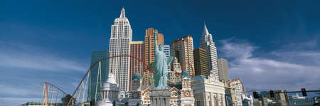 This is the New York, New York Hotel and casino during the day. The buildings show a replica of the Empire State Building, the Chrysler Building, the Statue of Liberty as well as other landmark New York buildings with a large roller coaster weaving in betのeditorial素材