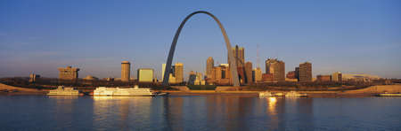 This is the skyline at sunrise. It is situated along the Mississippi River. There are riverboats on the water with the St. Louis Arch in clear view.のeditorial素材
