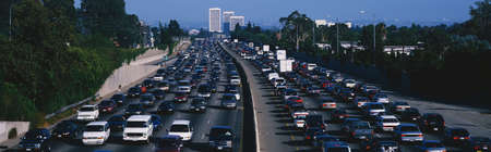 This is rush hour traffic on the 405 Freeway at sunset. There are 10 lanes of traffic total showing both sides of the freeway. There are cars stopped in every lane.のeditorial素材