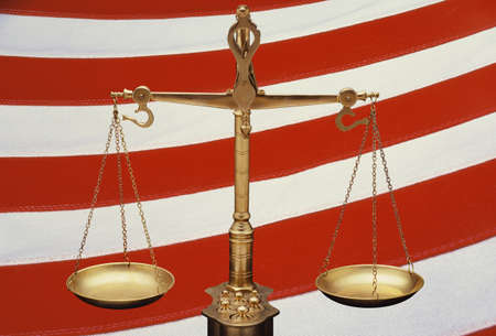 These are the golden Scales of Justice set against a background of the red and white stripes of the American flag. The scales are in a balanced position. This is a digitally created image.のeditorial素材