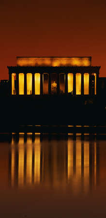 This is sunset at the Lincoln Memorial. An orange glow and reflection are shown in the reflecting pool in front of it.のeditorial素材