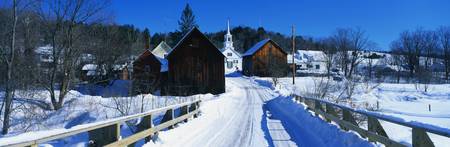 This is a small town in New England showing a white Methodist Church with steeple. There is a snow...