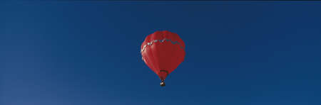 This is the 25th Annual Albuquerque International Balloon Fiesta. It shows a red balloon that is part of the mass ascension of colorful balloons.のeditorial素材