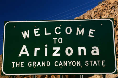 This is a road sign that says, Welcome to Arizona, The Grand Canyon State. It is against a blue sky.の写真素材