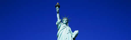 This is the top half of the Statue of Liberty against a blue sky in horizontal format.の写真素材