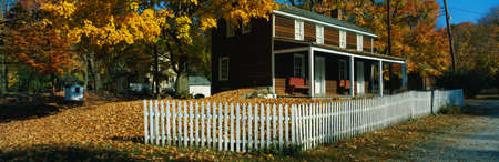This is a brown, wooden house in a historic village near the Delaware River. A white picket fence surrounds the house. There are autumn leaves on the trees surrounding the property.のeditorial素材