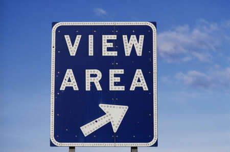 This is a road sign that says, View Area with a white arrow pointing to the right. The sign is against a blue sky with white clouds in the background.の写真素材