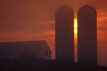 Silhouetted farm building and grain elevatorの写真素材