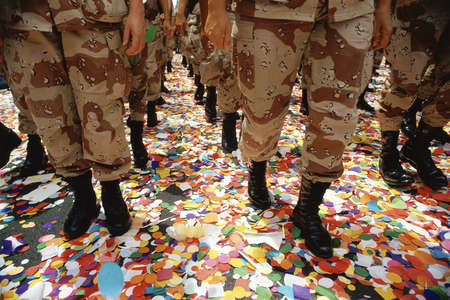 Legs of soldiers walking on confetti in paradeの写真素材