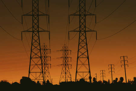 Power lines silhouetted by setting sunの写真素材