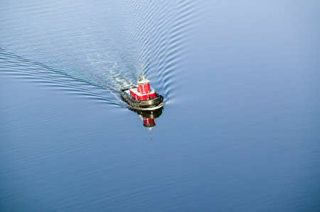 A aerial view of a bright red tug boat in blue water outside of Portland Maineのeditorial素材