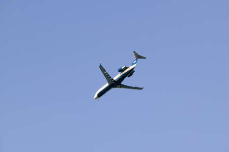 Commercial jet airplane flies overhead in a clear blue sky.