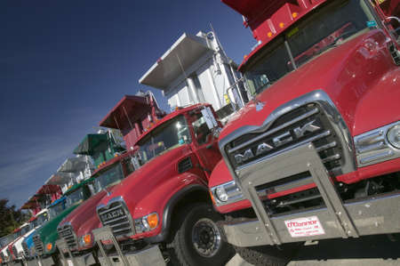 Bright red Mack dump trucks line the road in a row, in Maine near the New Hampshire borderのeditorial素材