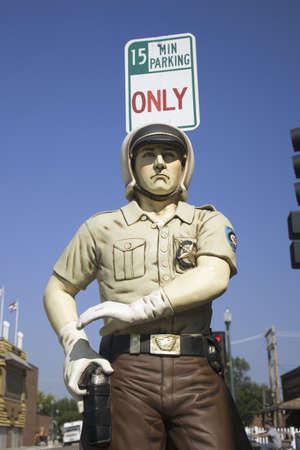 Fake policeman posing in front of sign saying 15 Minutes Parking Only, Mitchell, South Dakota