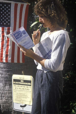 Woman voter reading election Sample Ballot at the entrance to a polling place, CAのeditorial素材