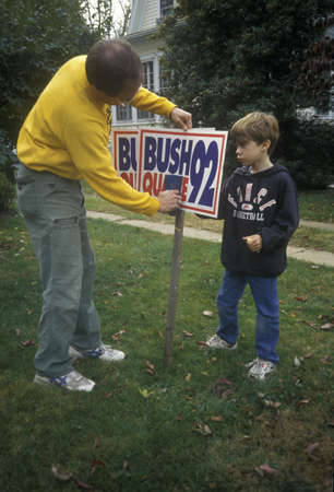 Man setting up Bush/Quayle 1992 campaign sign in his yardのeditorial素材