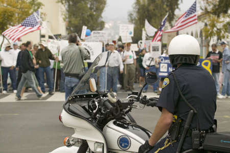 A motorcycle policeman looks at protesters against George W. Bush and the Iraq War at an anti-Iraq...