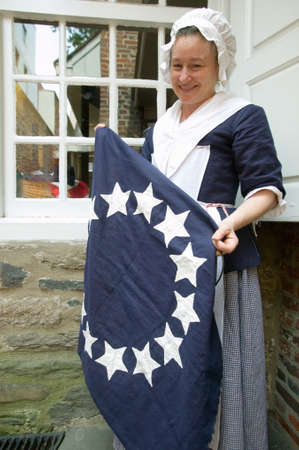 Betsy Ross actor holds colonial flag in The Betsy Ross House on East Third Street, Philadelphia, Pennsylvaniaのeditorial素材