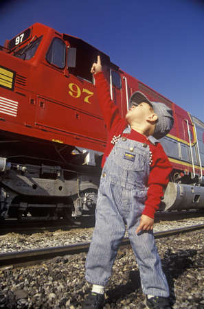 A little engineer in engineer cap with a historic Santa Fe Diesel train in Los Angeles, CA