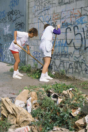 People cleaning area near wall covered with graffitiのeditorial素材
