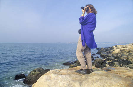 Woman photographs on the rocks of Bluff Point State Park, Groton, Connecticutのeditorial素材