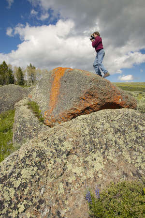 Photographer and ancient orange lichens growing on rocks in Centennial Valley near Lakeview, MTのeditorial素材