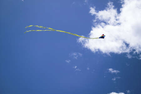 A rainbow colored kite flying in a blue sky with white puffy clouds on April 15, 2007, at the Santa Barbara Kite Festival, Santa Barbara City College, overlooking Pacific Ocean.のeditorial素材