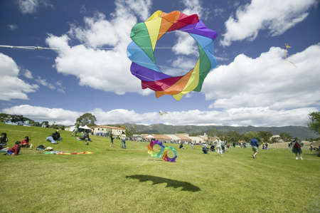 A rainbow colored kite flying in a blue sky with white puffy clouds on April 15, 2007, at the Santa Barbara Kite Festival, Santa Barbara City College, overlooking Pacific Ocean.のeditorial素材