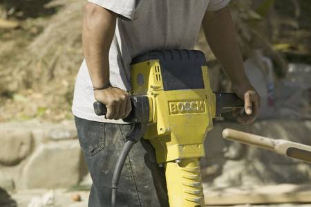 Man breaking concrete with yellow jackhammer
