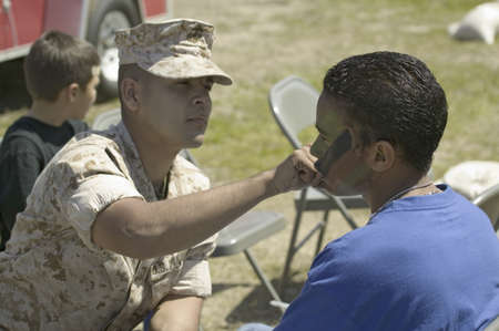 Army solider applying camouflage to young boy at the 42nd Naval Base Ventura County (NBVC) Air Show...