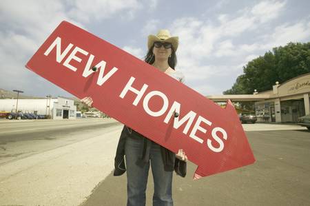 Girl holding red sign with arrow pointing down, that reads New Homes For Sale in Santa Paula, Californiaのeditorial素材