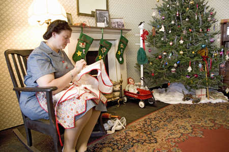 World War II woman actress sewing in 1940s style living room at Mid-Atlantic Air Museum World War II Weekend and Reenactment in Reading, PA held June 18, 2009のeditorial素材