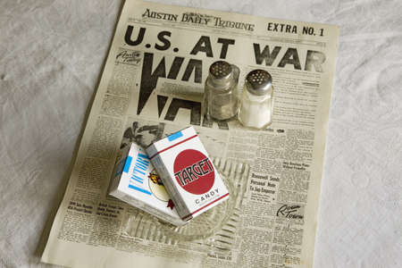 Still life of Austin Daily Tribune headline reading US AT WAR with Target candy cigarettes and salt and pepper shakers at Mid-Atlantic Air Museum World War II Weekend and Reenactment in Reading, PA held June 18, 2008のeditorial素材