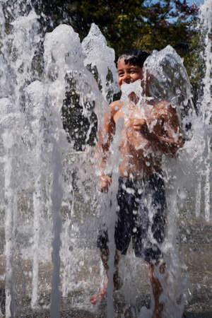A young boy playing in a water fountain のeditorial素材