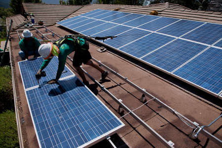 Workers installing a solar panel on a rooftop のeditorial素材