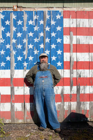 Man posing in front of a flag of the United States of America painted on an old barn in Maineのeditorial素材