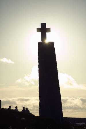 Cross with sun behind it at Cabo da Roca on the Atlantic Ocean in Sintra, Portugal, the westernmost...