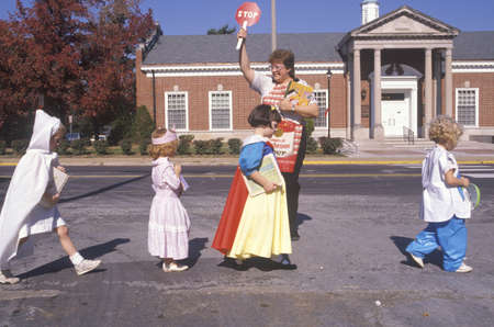 School crossing guard helping children in Halloween costumes, Webster Groves, Missouriのeditorial素材